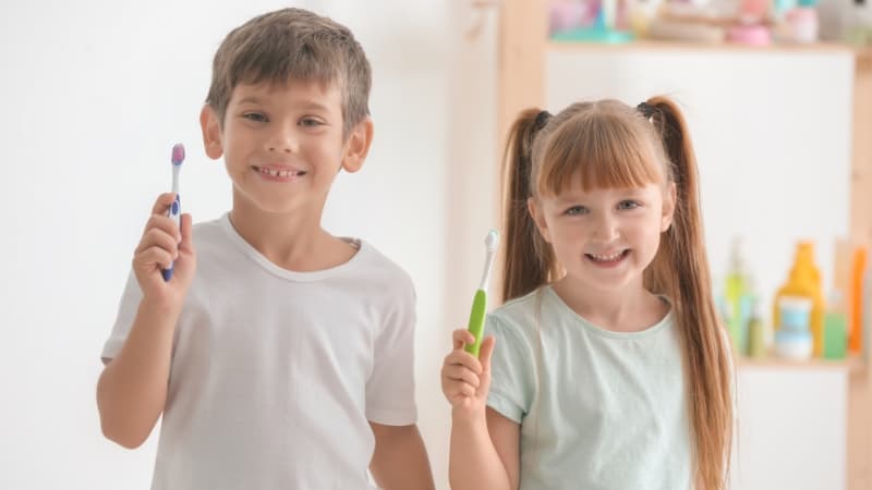Dzieci z szczoteczkami do zębów i plakatami o higienie